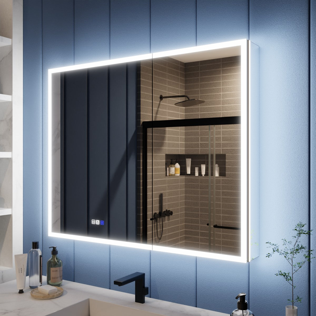 A rectangular LED-backlit bathroom mirror mounted on a blue paneled wall above a white sink. The mirror reflects a tiled shower area, and the sink counter has a few toiletry items and a small plant nearby.