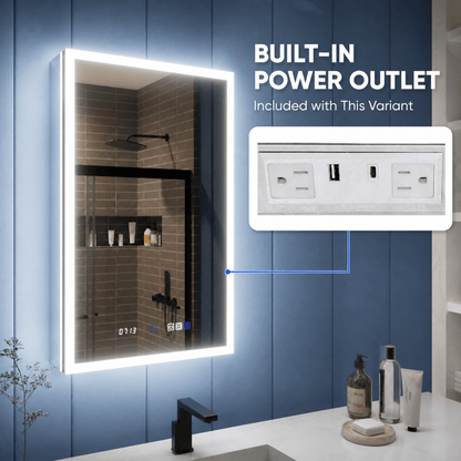 An illuminated rectangular bathroom mirror with a built-in power outlet, shown mounted on a blue paneled wall above a white countertop. Text on the image reads 'BUILT-IN POWER OUTLET Included with This Variant,' and a callout inset shows the outlet detail.